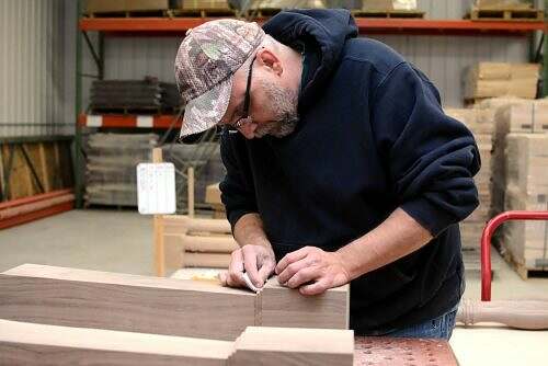 Craftsman putting the finishing touches by hand-sanding a custom wood square post