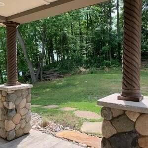 Exterior wood columns with rope details mounted on top of stone bases